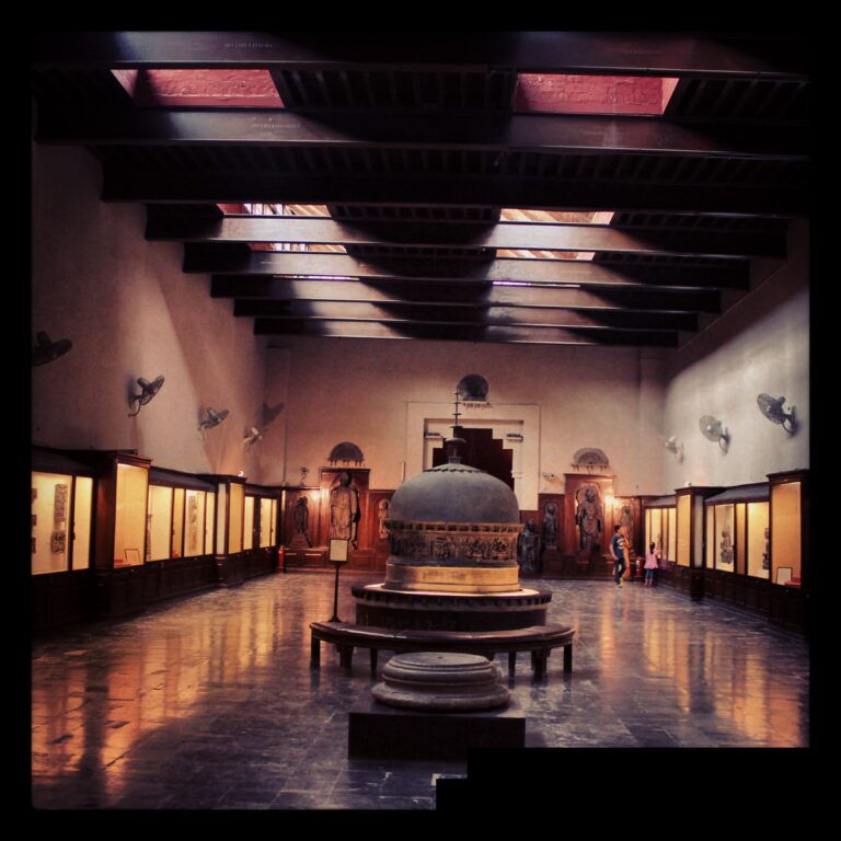 Interior view of a grand hall during an art exhibition Lahore, showcasing ancient sculptures and artifacts at a museum.